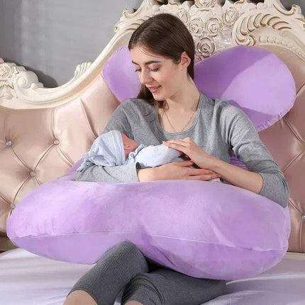 Woman holding a baby while sitting on a purple U-shaped 130x70cm Pregnancy Pillow in a bedroom setting.