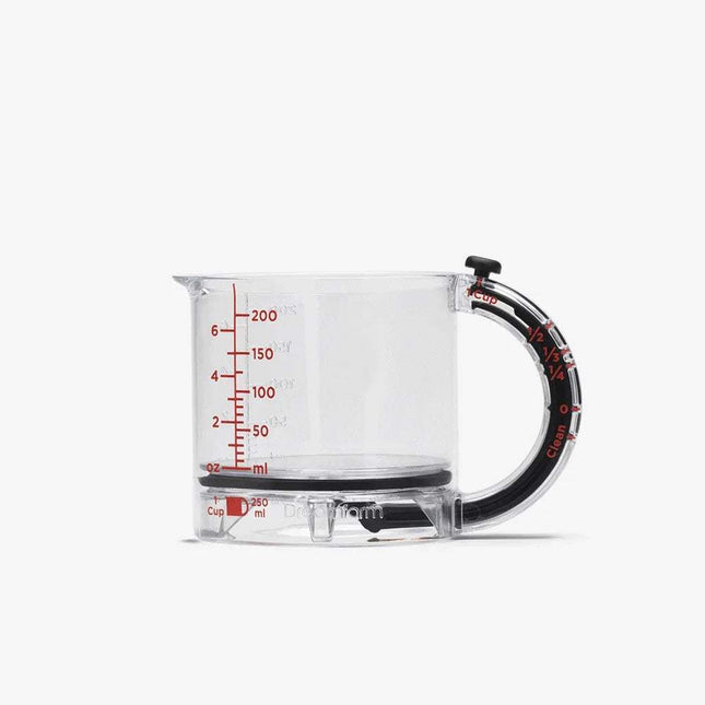 4-in-1 Adjustable Measuring Cup. Clear measuring cup with black handle and red measurement markings on a white background