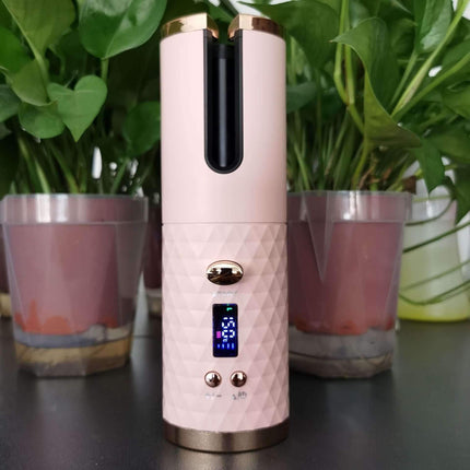 Cordless Hair Curler in pink design with LED display, surrounded by green plants.
