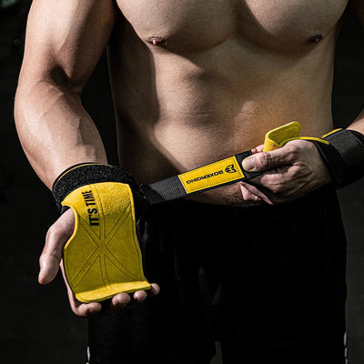 Person wearing yellow weightlifting grip pads with black straps on a dark background