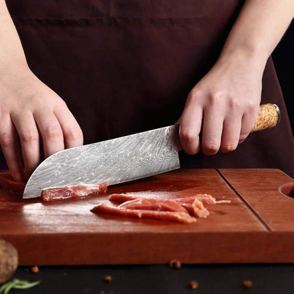7 Inch Chef Knife. Person cutting meat on a wooden board with a large knife