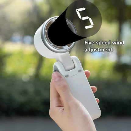 Handheld Turbo Fan. Hand holding a white device with 'Five-speed wind adjustment' text against a blurred green outdoor background