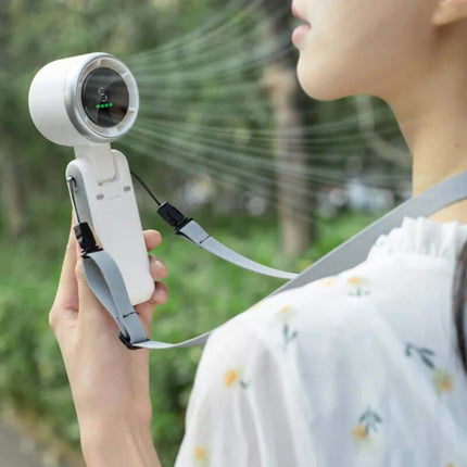 Handheld Turbo Fan. Person using a handheld device with a strap, possibly for cooling or treatment, outdoors.