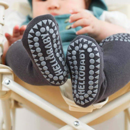Baby Knee Non-Slip Floor Socks Baby's feet wearing dark gray socks with 'HELLOBABY' branding, sitting on a light-colored surface.