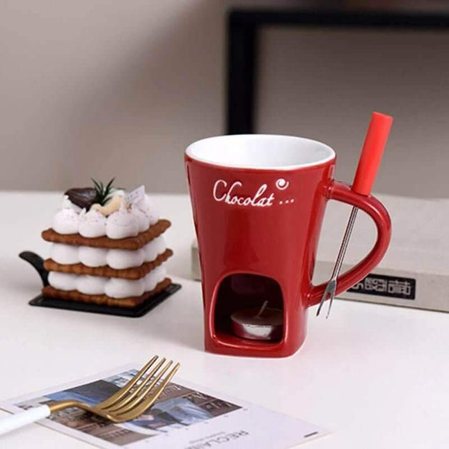 Ceramic Fondue Mug red with a straw and chocolate-themed design on a table with a dessert and newspaper.