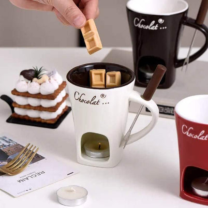 Ceramic Fondue Mug with 'Chocolat' branding being used to melt chocolate, with a small cake and candle in the background.