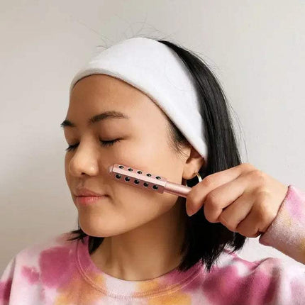 Person using a pink Germanium Beauty Roller  with a neutral background