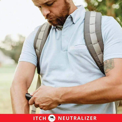 Man with a backpack using an Itch Relief Pen outdoors