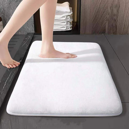 Memory Foam Bathroom Mat. White bath mat on a bathroom floor with a person stepping onto it.