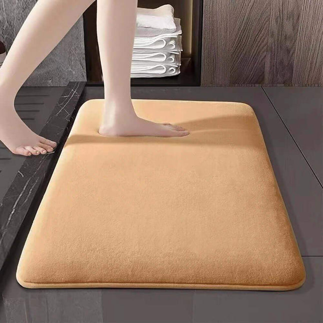 Memory Foam Bathroom Mat. Beige bath mat on a bathroom floor with legs stepping onto it
