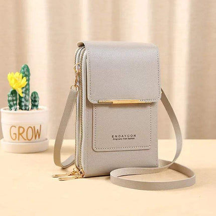 Light gray Small Bag for Females with Transparent Touch Screen Area with gold accents on a beige surface with a cactus plant in the background.