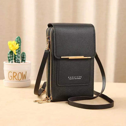 Black Small Bag for Females with Transparent Touch Screen Area with gold accents on a beige surface with a plant in the background