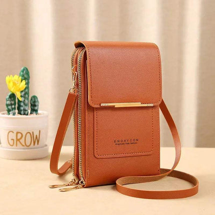 Brown Small Bag for Females with Transparent Touch Screen Area with gold accents on a beige surface with a plant in the background