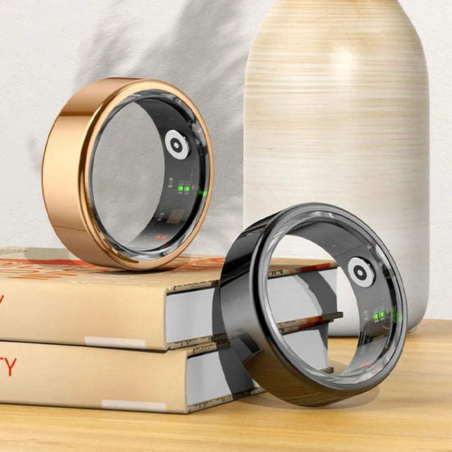 Two Smart Ring with digital displays on a wooden surface with books and a vase in the background. Astoria Lifestyle