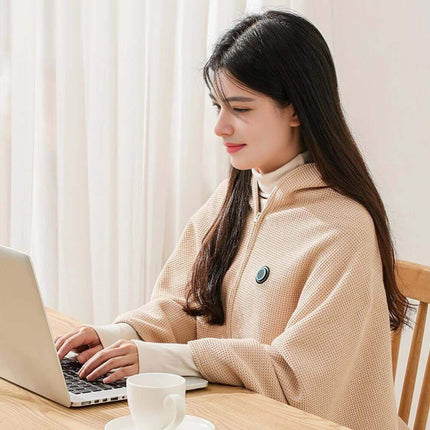 Woman wearing a Wearable Electric Heating Blanket while using a laptop at a table with a cup of coffee, sitting for cozy warmth.