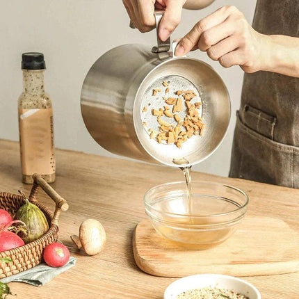 Hands pouring fried food residues into a bowl using a Stainless Steel Frying Pot Even & Crispy Frying Made Easy.