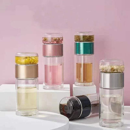 Set of clear glass Tea Infuser Bottle with different contents on a pink background
