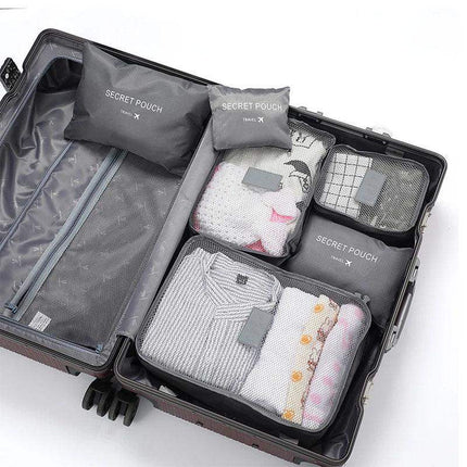 Open suitcase with folded clothes and gray 6Pcs Travel Clothes Storage Bags labeled 'Secret Pouch' on a white background.