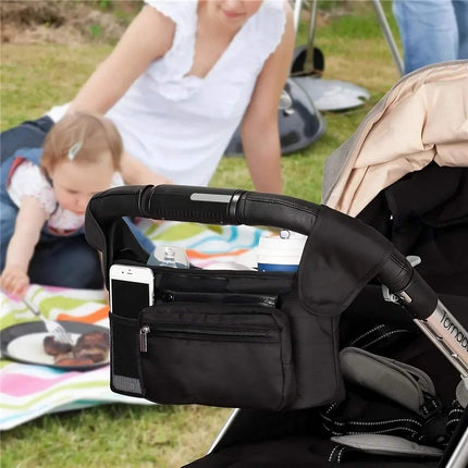 Black Baby Stroller Organizer Convenient Storage for Parents on the Gowith phone holder attached to a stroller, with a child and adult in the background.