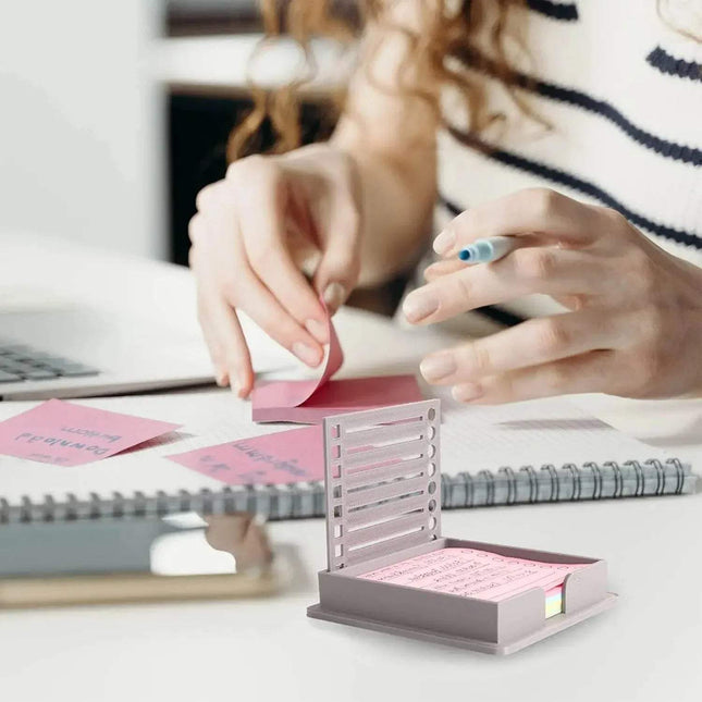 Person using a Sticky Note Holder with Template with pink sticky notes on a desk.