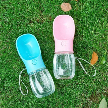 Portable Pet Water Drinking Bottle in blue and pink colors on green grass.