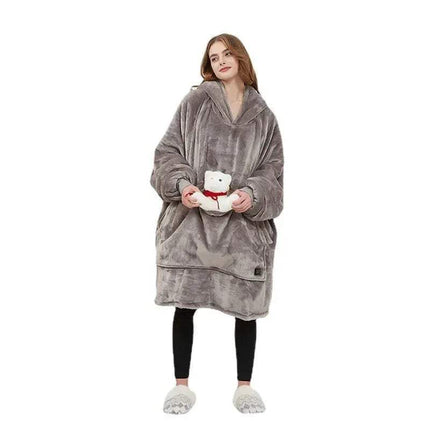 Person wearing a gray fleece Oversized Heatable Hoodie holding a small white bear plush toy on a white background