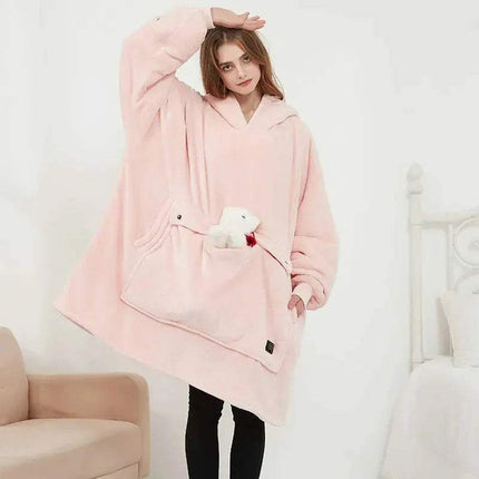 Person wearing a pink Oversized Heatable Hoodie with a white teddy bear in a room.