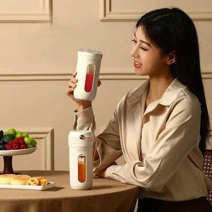 Woman holding a 10 Blades Electric Portable Blender with a red liquid, sitting at a table with food.