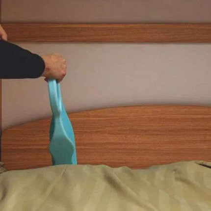 Person holding a blue Ergonomic Mattress Wedges over a wooden bed frame.