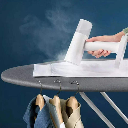 Person using a Handheld Garment Steamer on a shirt with clothes hanging below an ironing board against a blue background