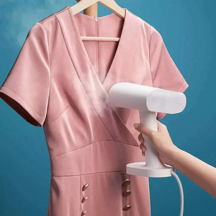 Handheld Garment Steamer using on a pink dress on a hanger for Fast Wrinkle-Free Clothes 