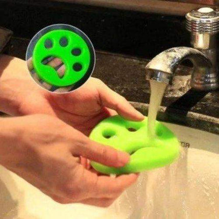 Person holding a green Pet Hair Remover Effortlessly Remove Fur from Clothes & Fabrics under running water in a sink.