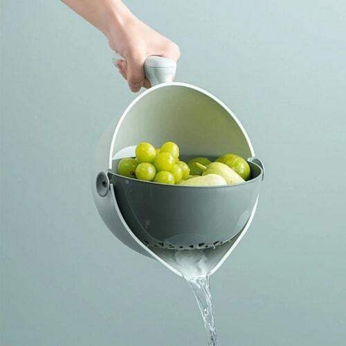 Person pouring water from a modern Rotating Draining Basket Quick & Easy Food Strainer for Kitchen with grapes into a sink.