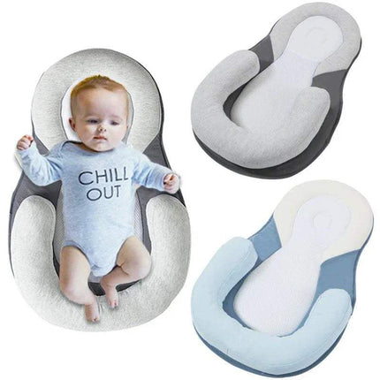 Baby in a 'Chill Out' onesie surrounded by Baby Anti-Rollover Sleeping Pillow in gray and blue.