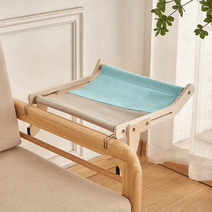 Sturdy Hanging Cat Bed with a blue and gray cushion on a beige sofa in a room with white walls and a plant.