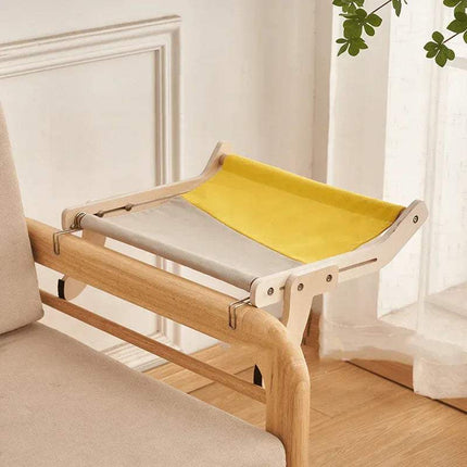 Sturdy Hanging Cat Bed with yellow and gray cushion attached to a sofa in a room with white walls and a plant.