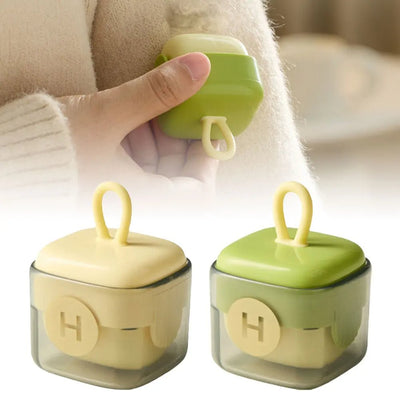 Two glass containers with green lids held by a hand, with a blurred background.