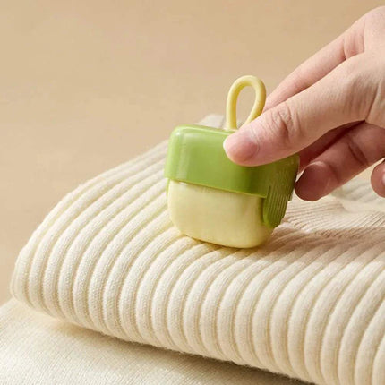 Hand holding a Portable Fur Remover on a beige fabric background