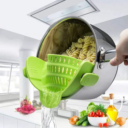 Green Universal Silicone Strainer Clip being used to drain pasta from a pot in a kitchen setting.
