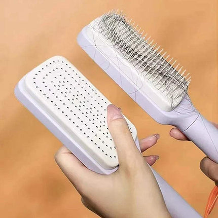White Self-Cleaning Hairbrush Hassle-Free Grooming & Smooth Styling with bristle head held by a hand against an orange background