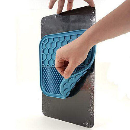Person placing a blue Slow Feeder Mat for Pets with honeycomb pattern onto a black surface
