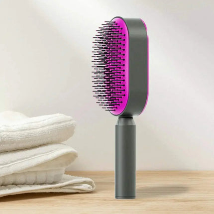 Ergonomic Hair Brush with pink bristle head on a wooden surface with white towels in the background