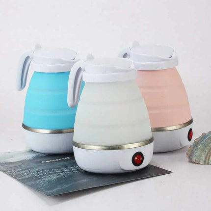 Folding Kettle & Water Heater for Travel & Convenience in white, blue, and pink on a white surface with a magazine underneath.