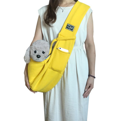 Person wearing a yellow sling bag with a small gray teddy bear inside, on a white background