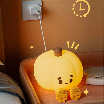 Cute Pumpkin Night Light on a wooden surface with a wall socket in the background.