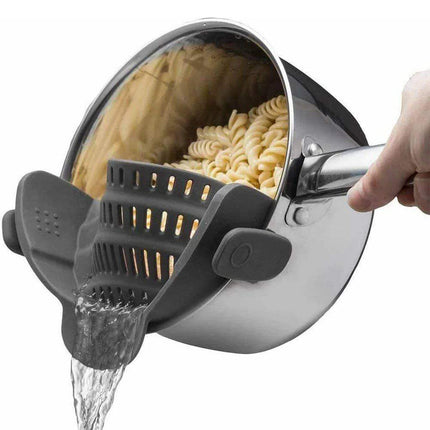 Pasta being drained from a pot with a gray Universal Silicone Strainer Clip.